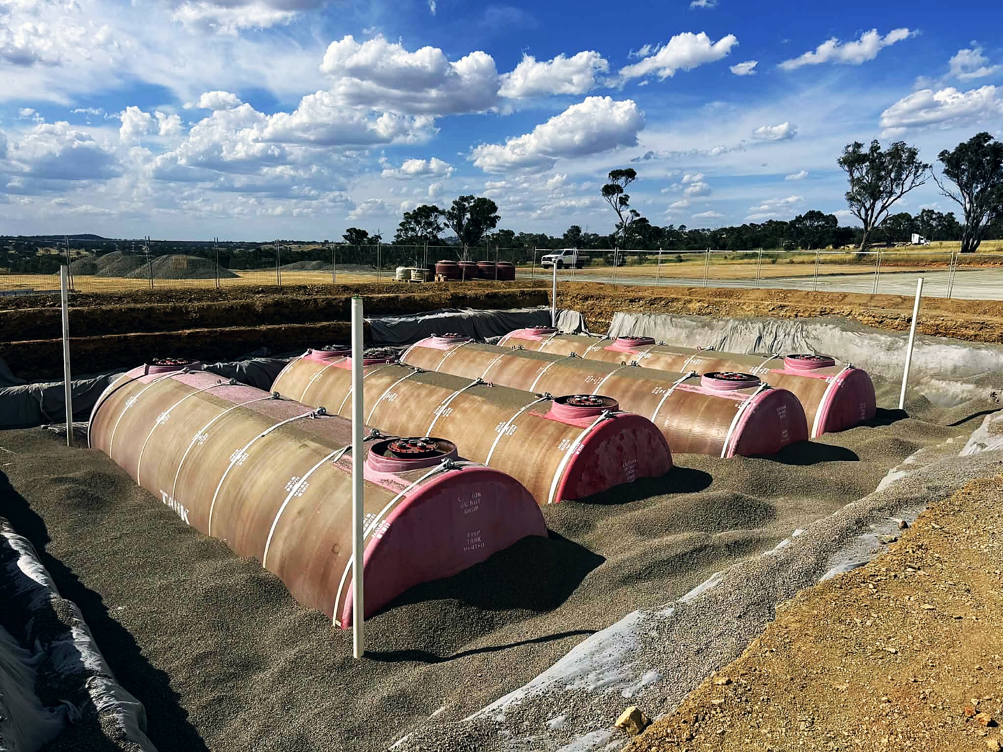 Underground fuel tanks laid out in an excavation ready for backfill